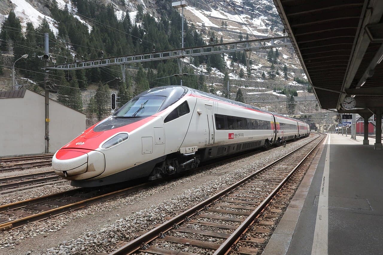 SBB Astoro (ETR 610) tilting train with its long red-and-white nose at Göschenen station, mountains behind