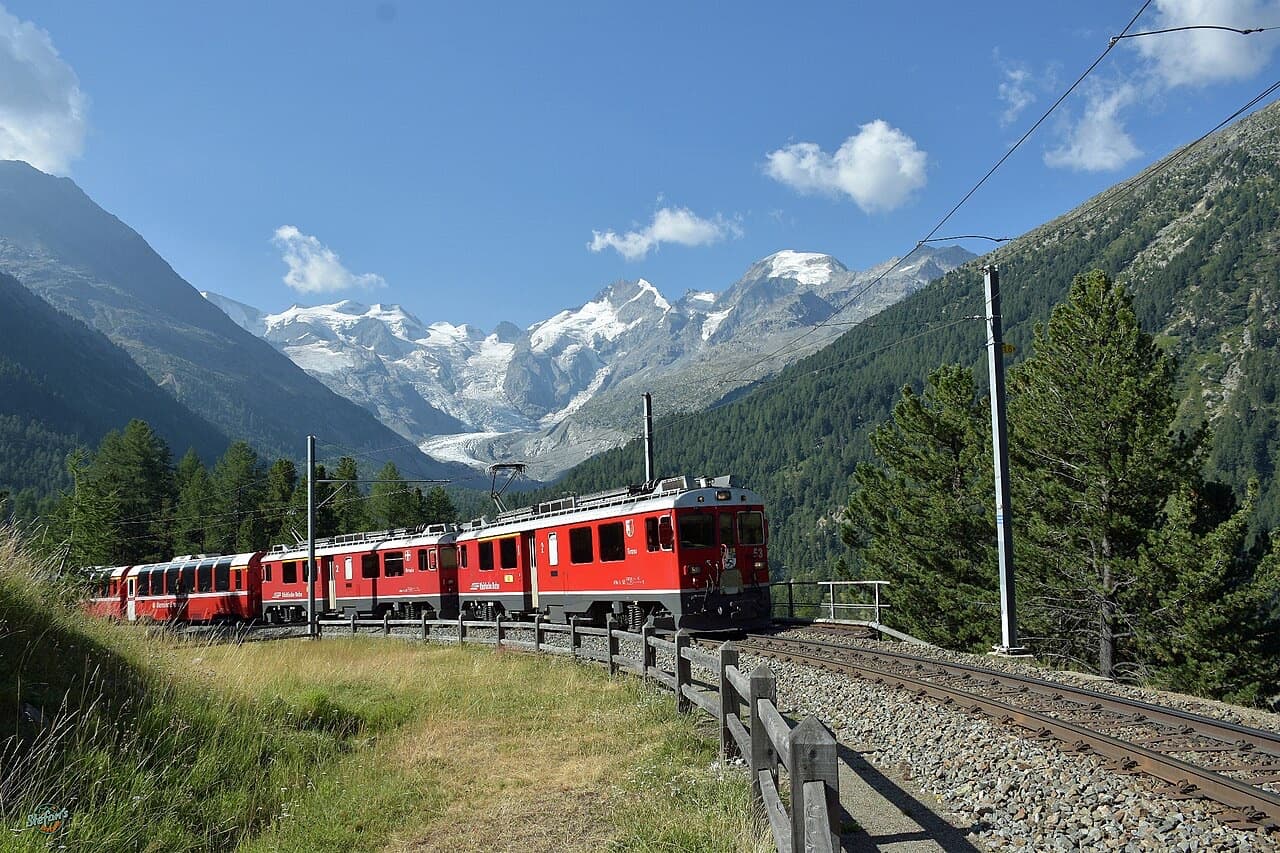 Bernina Express led by two RhB ABe 4/4 III railcars near Morteratsch, panorama coaches at the rear, Bernina massif behind