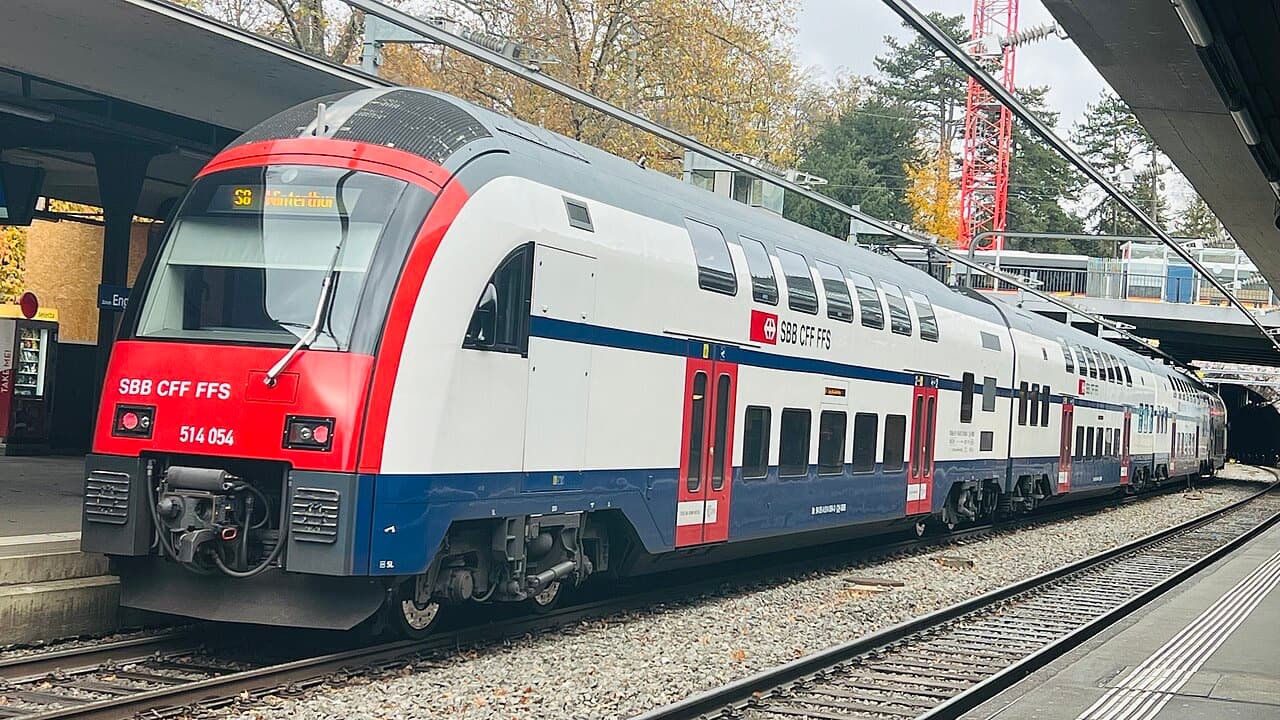 Double-deck DTZ S-Bahn unit with red front, white upper deck and blue lower band at a platform in Zürich