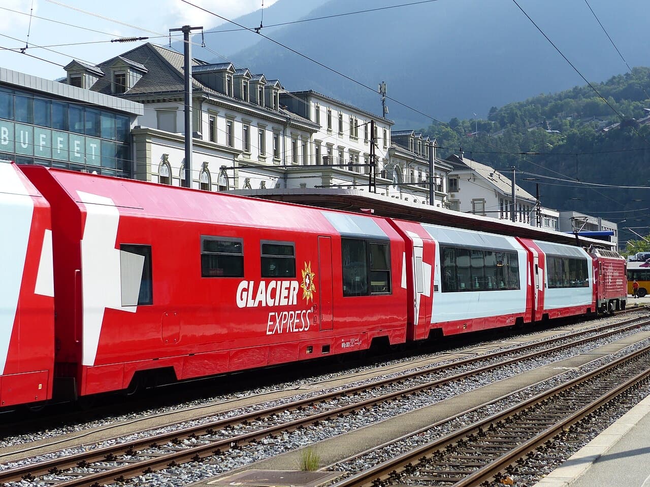 Glacier Express panorama coaches with red livery and lettering at Brig, locomotive at the far end