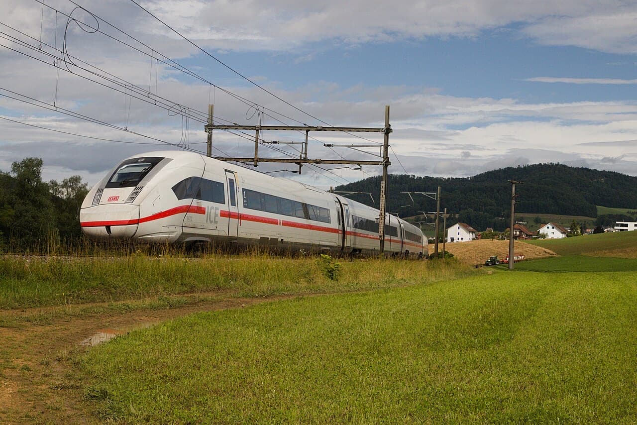 DB ICE 4 in white with red stripe, front three-quarter view, running past fields near Tecknau in Switzerland