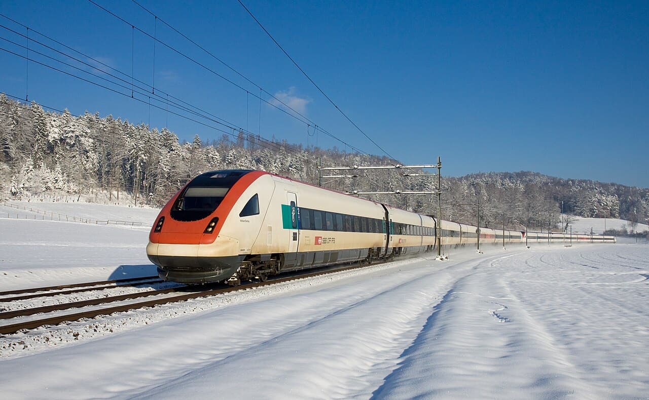 SBB ICN tilting train with its pointed red nose crossing a snowy field between Elgg and Schottikon