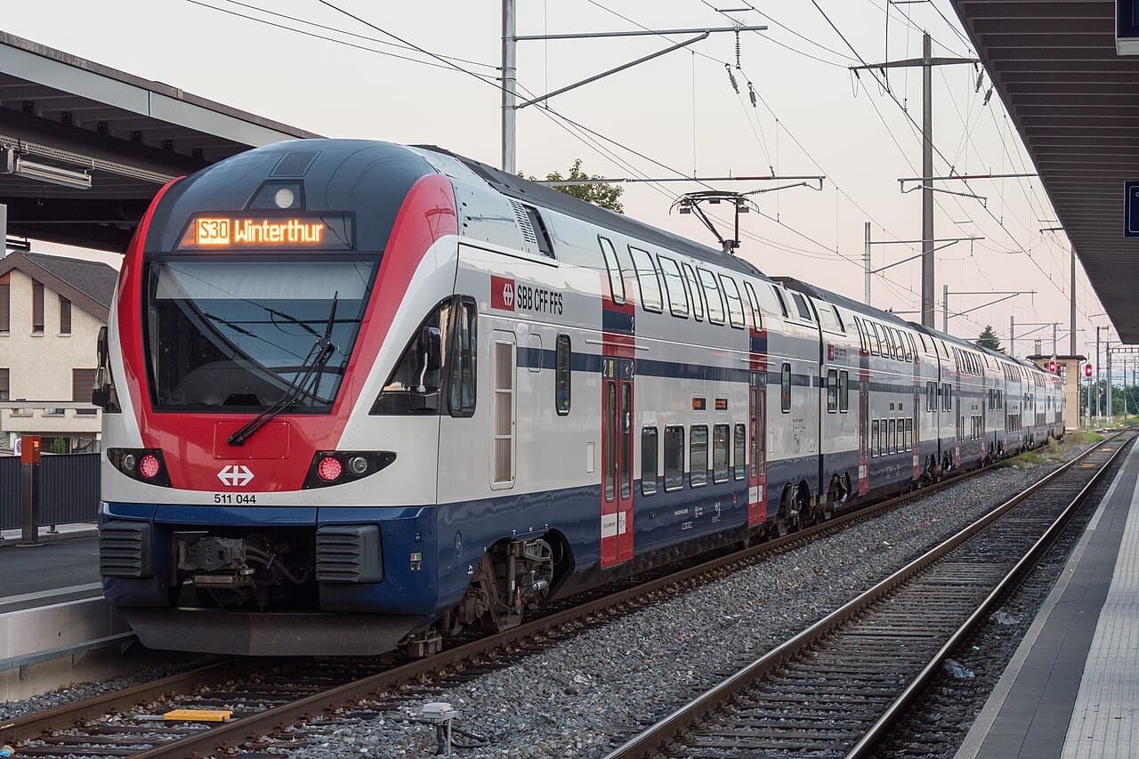 White double-deck KISS train with rounded red-edged nose at a station platform
